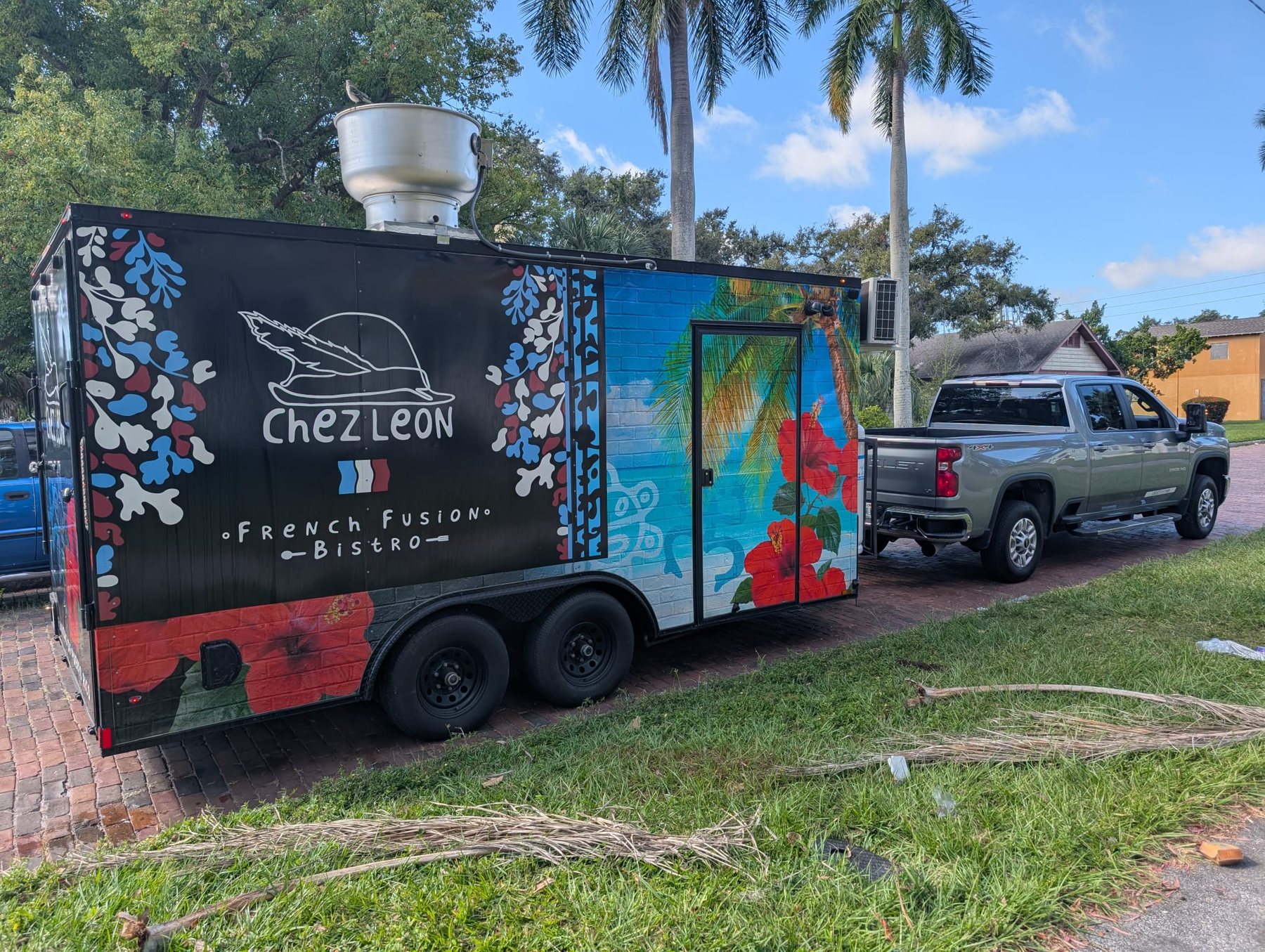 The Chez Leon food truck parked in Tampa, painted with hibiscus flowers and the French flag colors.