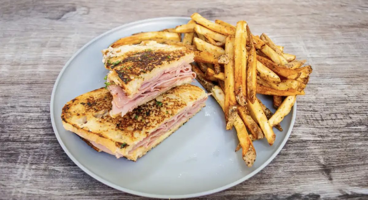 Croque Monsieur sandwich sliced in half, served with seasoned fries.