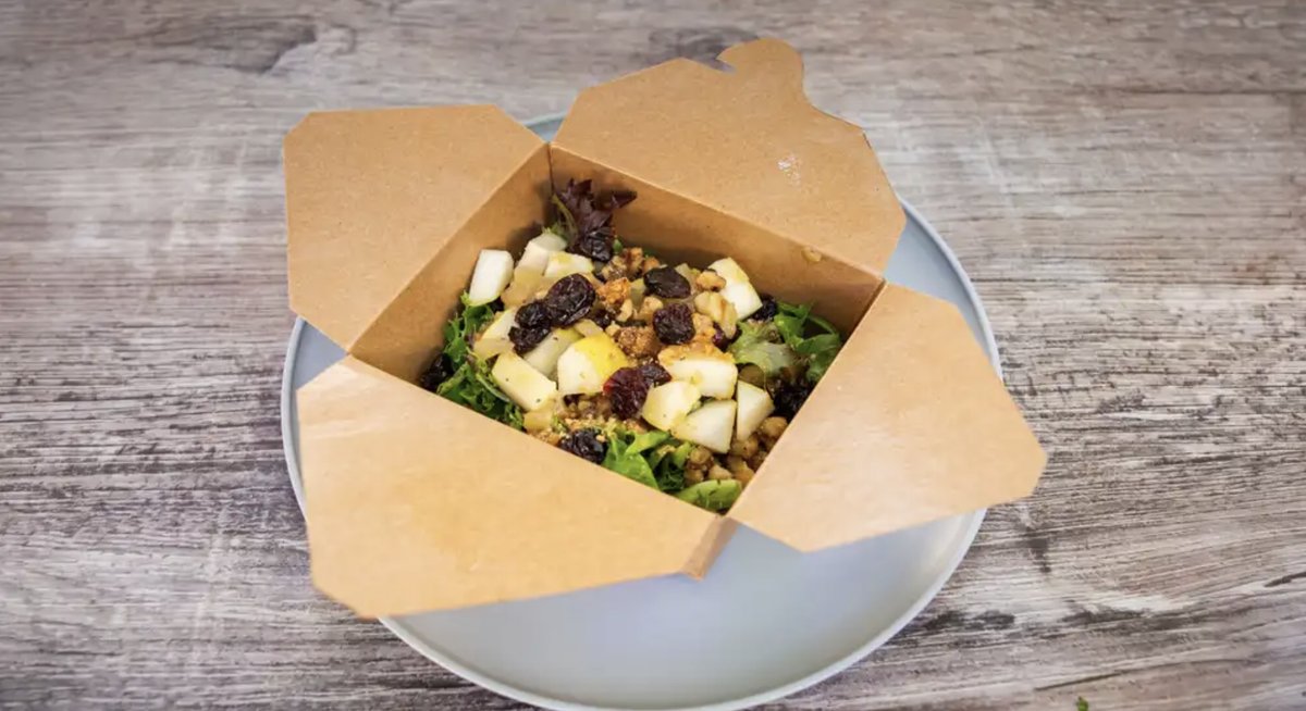 The Naughty Pear Salad with mixed greens, pears, walnuts, and dried cranberries in a to-go box.